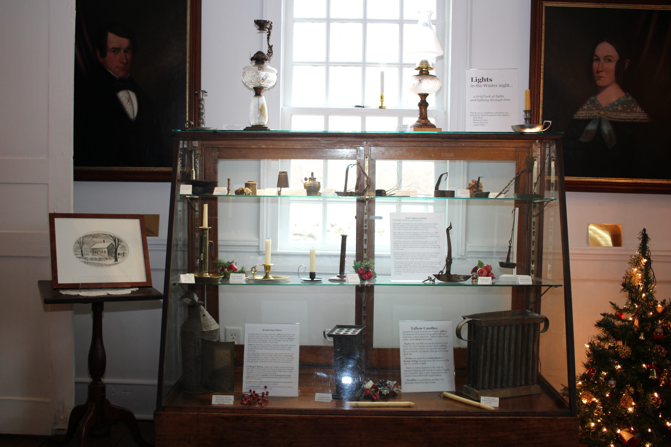 A vintage display case from Oxford's Devaux store filled with lighting items of all ages. Portraits in rear are David Tomlinson and Mary Lum who acquired the Oxford House in 1865.